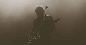 A guitarist performing on a dark stage.