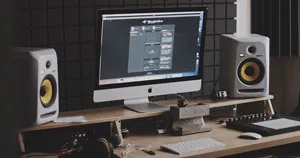 A computer screen and studio monitors placed on a desk.