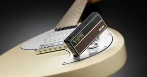 A portable amp plugged into the output jack of an electric guitar.