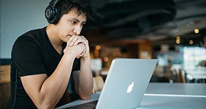An image of a man looking at a MacBook.